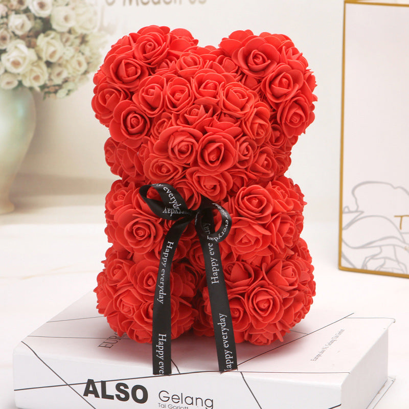 Ours créatif en roses rouges avec nœud noir décoratif sur boîte blanche.
