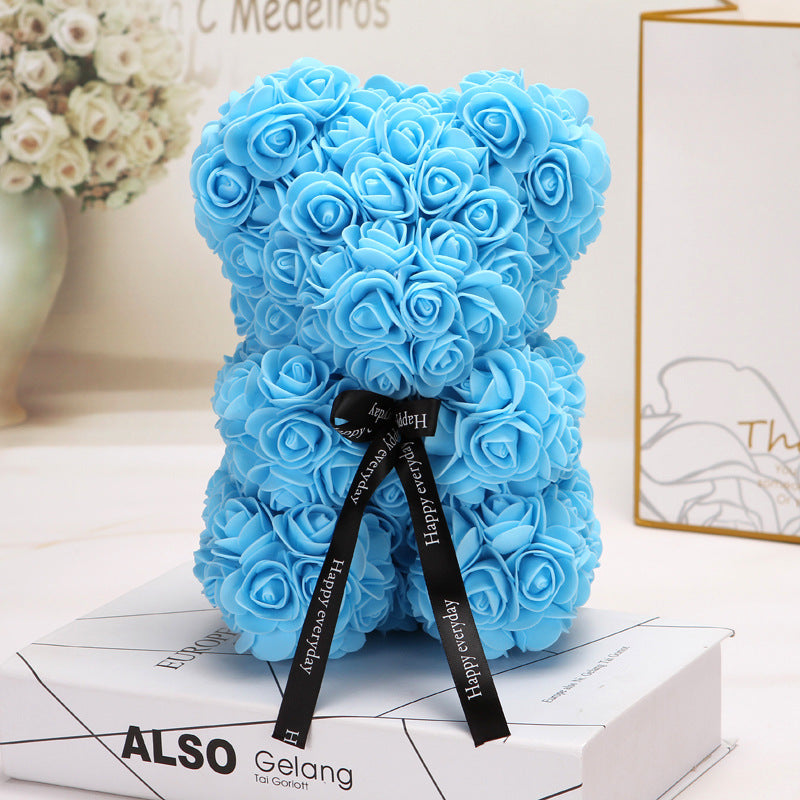 Ours créatif en roses bleues avec ruban noir décoratif, sur boîte blanche élégante.