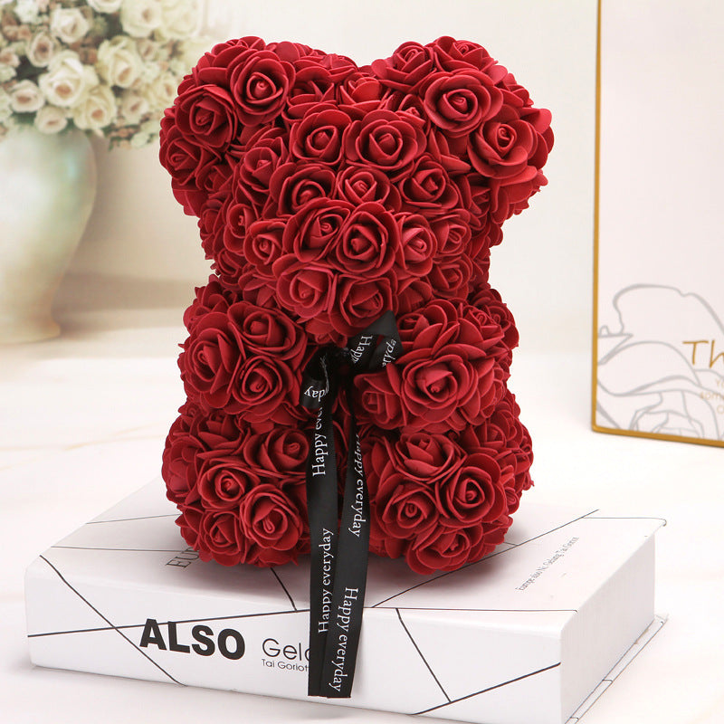 Ours créatif en roses rouge décoratif avec ruban noir posé sur un livre blanc