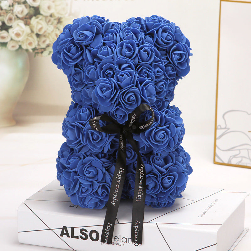 ours créatif fait de roses bleues avec un ruban noir "Happy everyday" posé sur un livre blanc